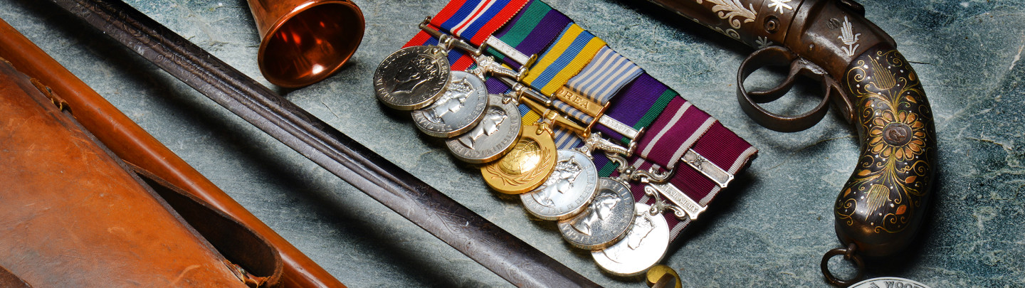 A collection of military antiques, medals, swords and a gun